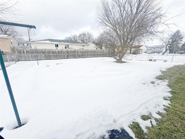 snowy yard with a fenced backyard