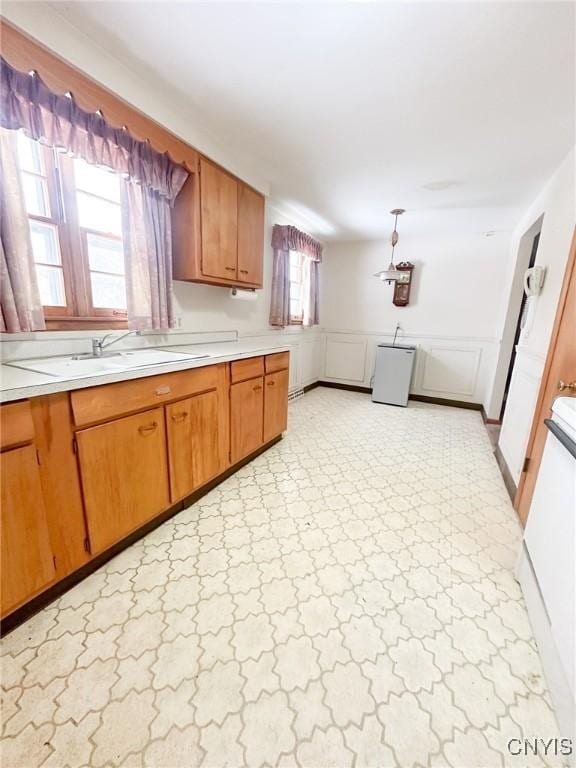 kitchen with brown cabinetry, light countertops, and a sink