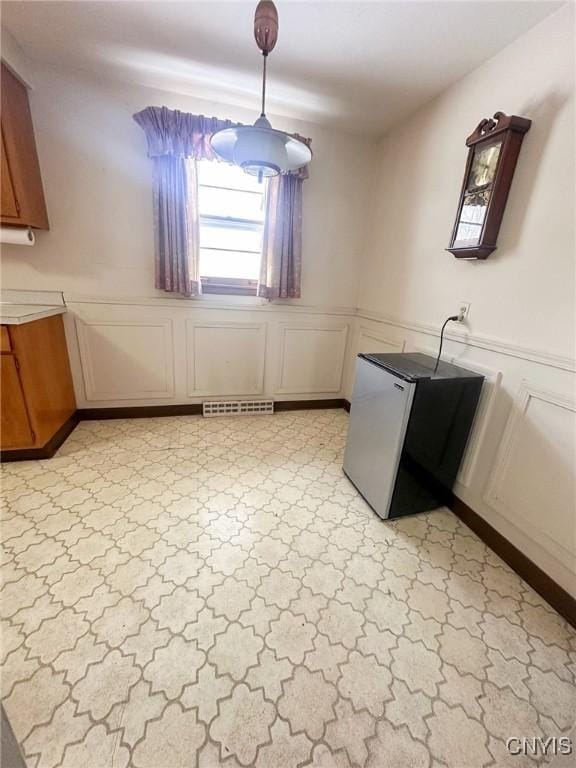 unfurnished dining area featuring wainscoting, visible vents, and a decorative wall