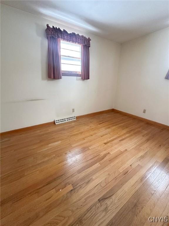 unfurnished room featuring light wood-style flooring, visible vents, and baseboards