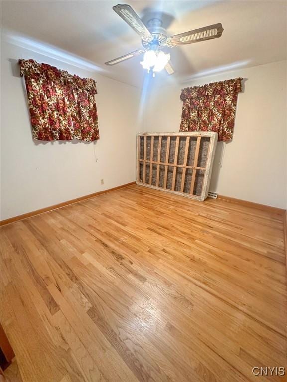 unfurnished living room featuring ceiling fan, baseboards, and wood finished floors