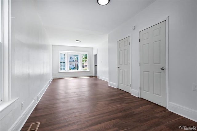 hallway with dark wood-style floors, visible vents, and baseboards