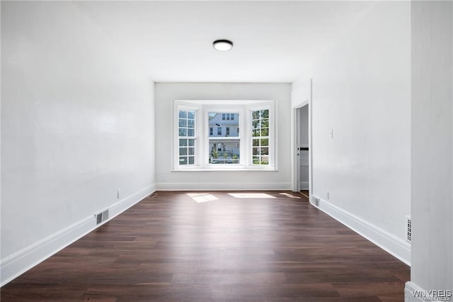 spare room featuring dark wood-style floors, visible vents, and baseboards