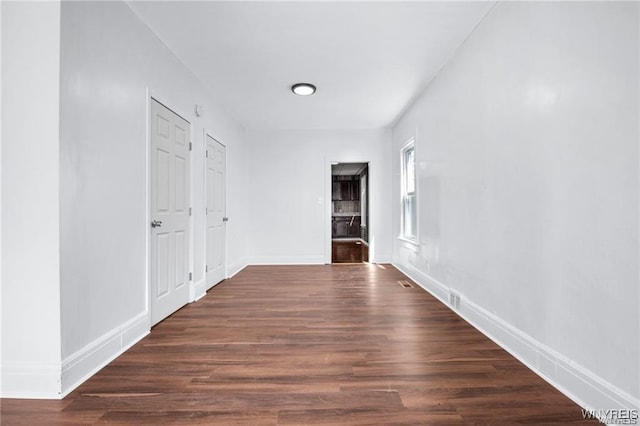 hallway featuring wood finished floors, visible vents, and baseboards