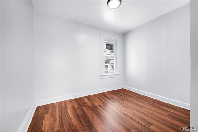 empty room featuring dark wood finished floors and baseboards