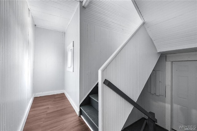 stairway with metal wall, wood finished floors, and baseboards