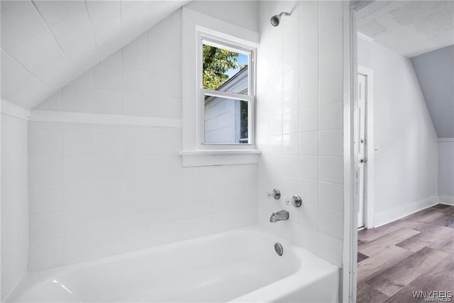 full bath with lofted ceiling, wood finished floors, a bath, and baseboards