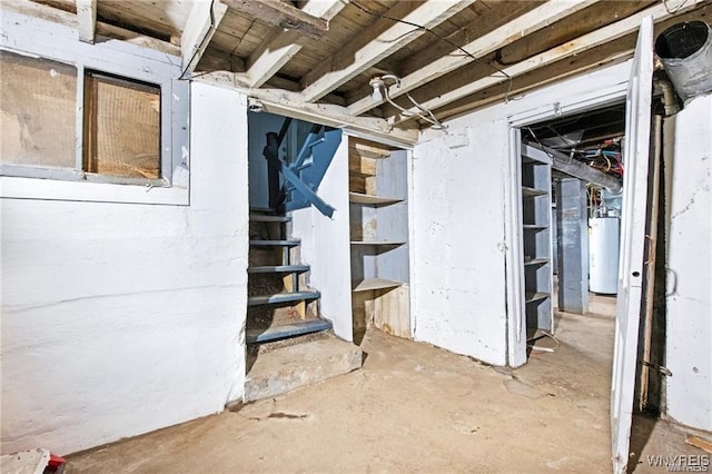 unfinished basement featuring water heater and stairway