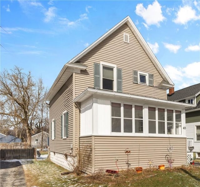 view of side of home featuring fence and a sunroom