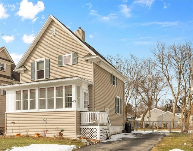 exterior space with a sunroom, fence, and a chimney