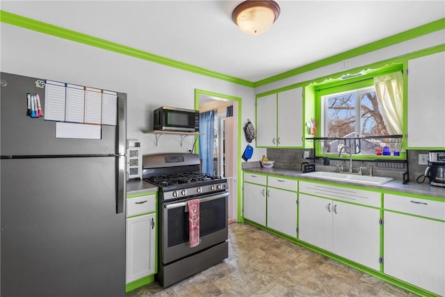 kitchen with light countertops, appliances with stainless steel finishes, a sink, and white cabinetry