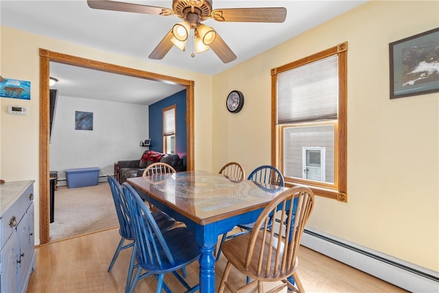 dining space featuring a baseboard heating unit, light wood finished floors, and a ceiling fan