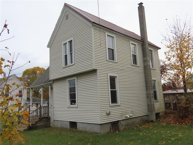 rear view of house featuring a chimney, metal roof, and a yard