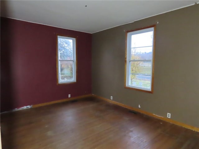 spare room featuring baseboards and wood finished floors