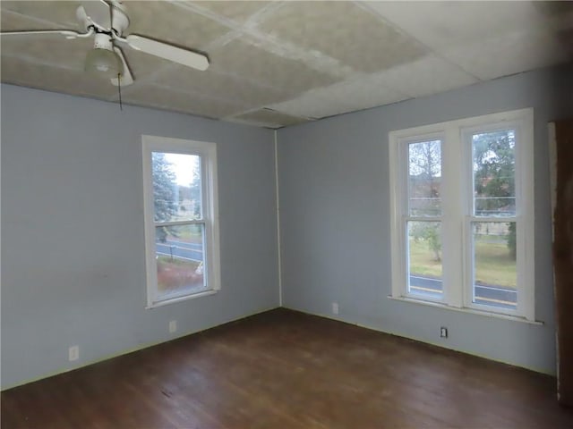 spare room featuring a ceiling fan, a wealth of natural light, and dark wood-style floors