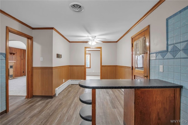 bar with a baseboard heating unit, a wainscoted wall, visible vents, and wood finished floors