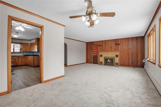 unfurnished living room featuring ornamental molding, carpet, a fireplace, and arched walkways