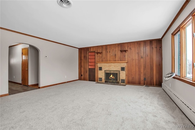 unfurnished living room featuring visible vents, arched walkways, a baseboard radiator, crown molding, and carpet flooring