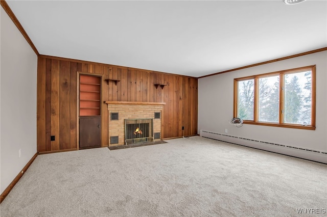 unfurnished living room featuring built in shelves, a fireplace, a baseboard heating unit, ornamental molding, and wood walls