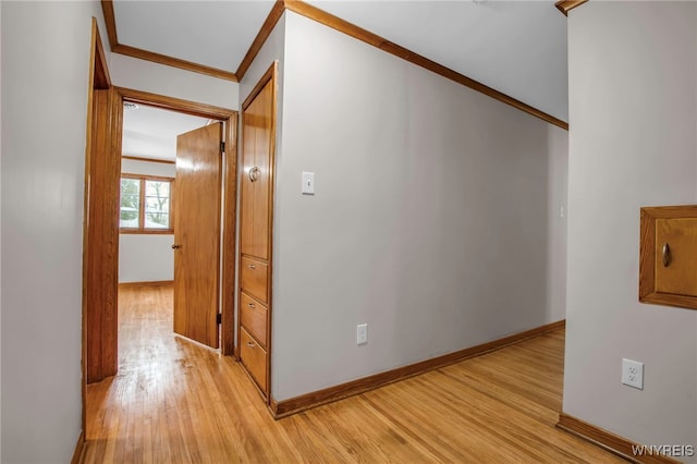 hallway featuring light wood-style flooring, baseboards, and crown molding