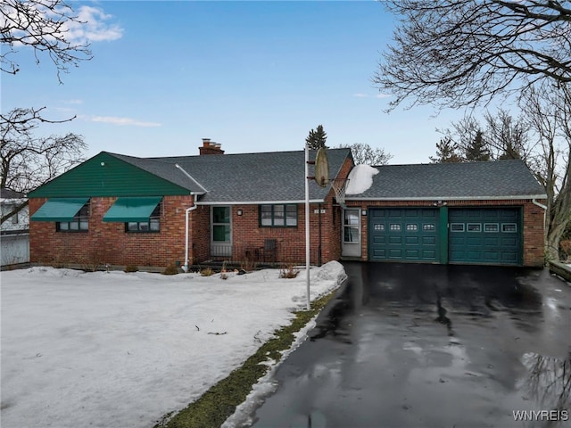 single story home featuring a garage, a chimney, aphalt driveway, and brick siding