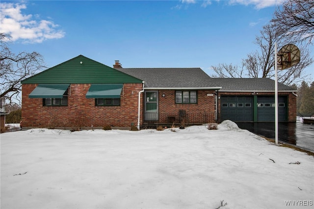 single story home featuring an attached garage, a chimney, aphalt driveway, and brick siding