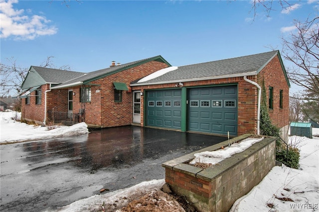 view of front of home with driveway, an attached garage, a shingled roof, and brick siding