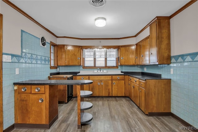 kitchen with light wood finished floors, visible vents, and brown cabinetry