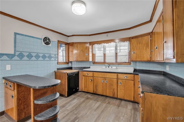 kitchen with dark countertops, black dishwasher, brown cabinets, and a sink