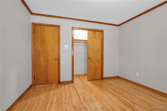 unfurnished bedroom with light wood-type flooring, a closet, crown molding, and baseboards