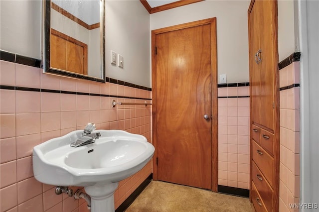 bathroom with wainscoting, a sink, and tile walls