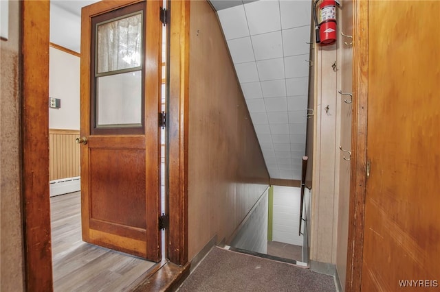 hall with a baseboard heating unit, a wainscoted wall, and wood finished floors