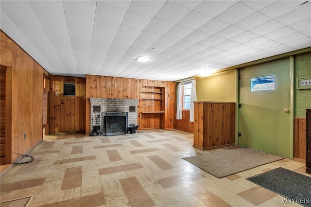 unfurnished living room featuring wood walls, a brick fireplace, and light floors