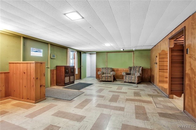 living area featuring wainscoting, wood walls, and tile patterned floors