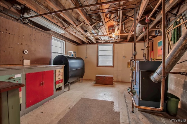 basement featuring concrete block wall, a healthy amount of sunlight, and heating fuel