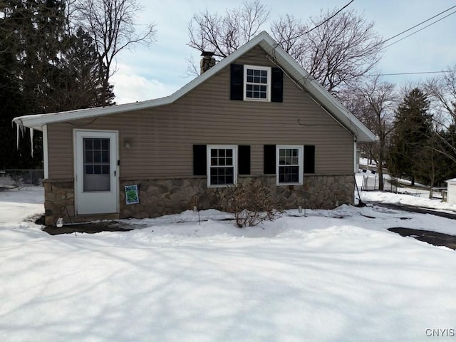 view of front of house with stone siding and a chimney