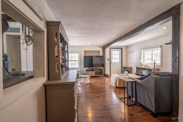 living room featuring recessed lighting, beam ceiling, a healthy amount of sunlight, and dark wood finished floors