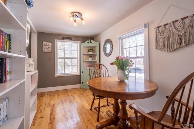 dining area with light wood-type flooring and baseboards