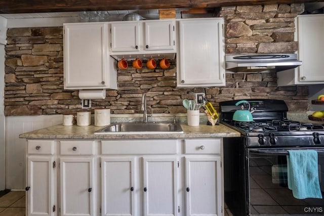 kitchen featuring white cabinetry, a sink, black gas range oven, and exhaust hood