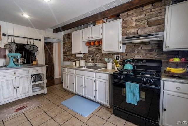 kitchen featuring light tile patterned floors, white cabinets, black gas range oven, ventilation hood, and a sink