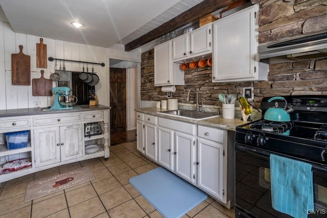 kitchen featuring black gas range oven, white cabinets, a sink, and exhaust hood