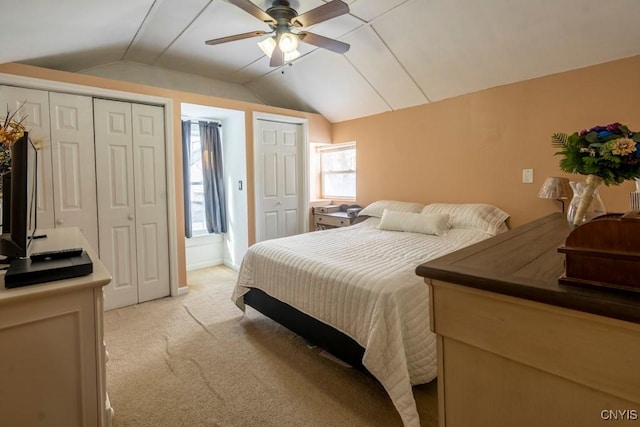 bedroom with multiple closets, lofted ceiling, light carpet, and a ceiling fan