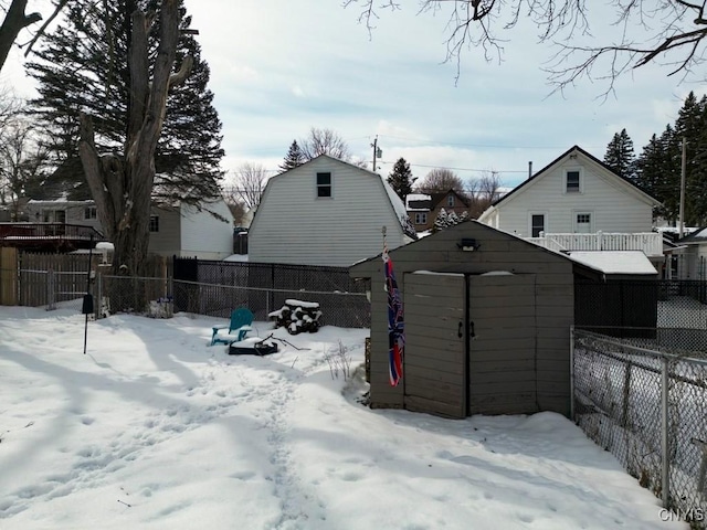 yard covered in snow featuring an outbuilding, a storage unit, and a fenced backyard