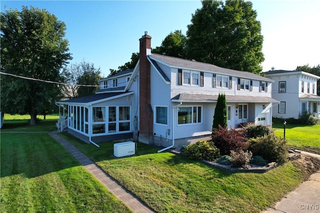 view of front of property featuring a sunroom, a chimney, and a front yard