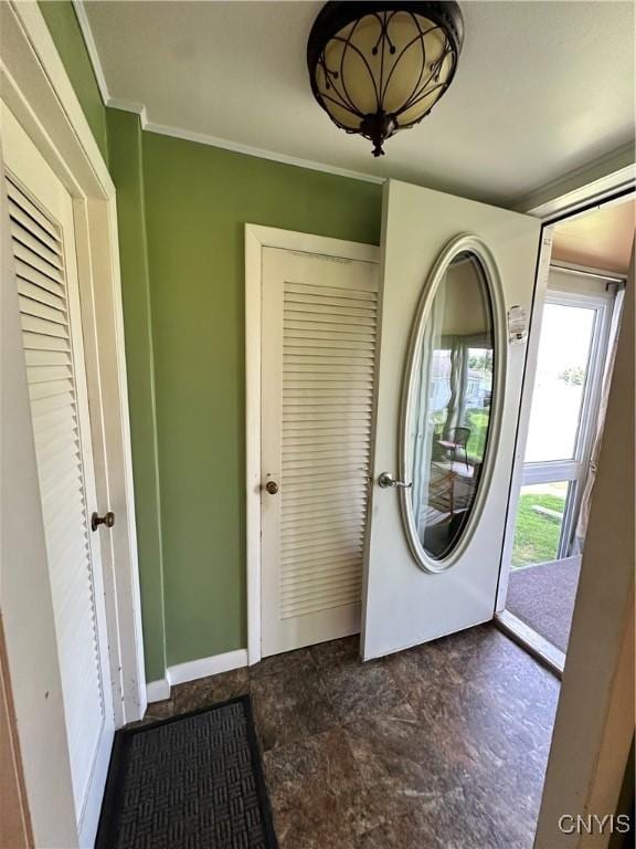 doorway featuring baseboards and crown molding