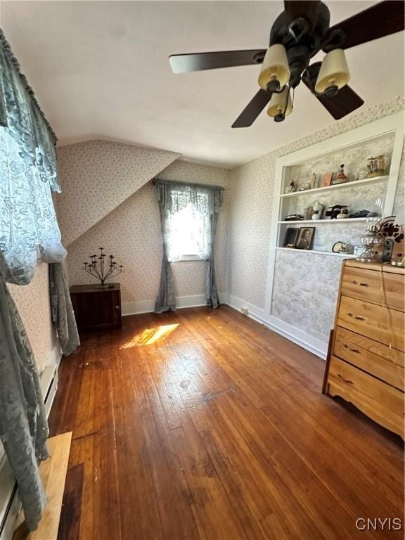 additional living space featuring a baseboard radiator, a ceiling fan, baseboards, hardwood / wood-style floors, and wallpapered walls