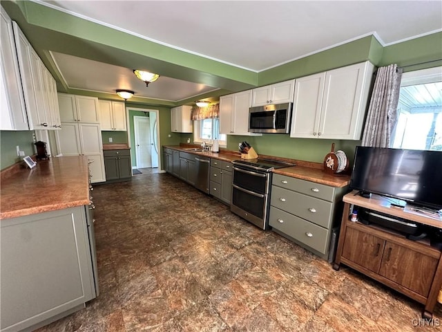 kitchen featuring white cabinetry, stainless steel appliances, a sink, and ornamental molding