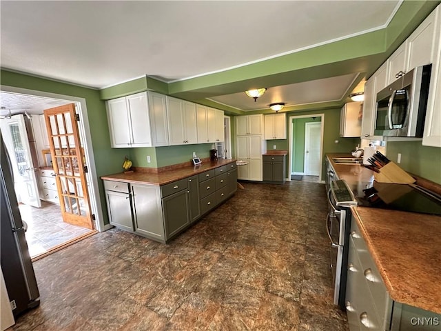 kitchen with baseboards, white cabinets, dark countertops, stainless steel appliances, and a sink