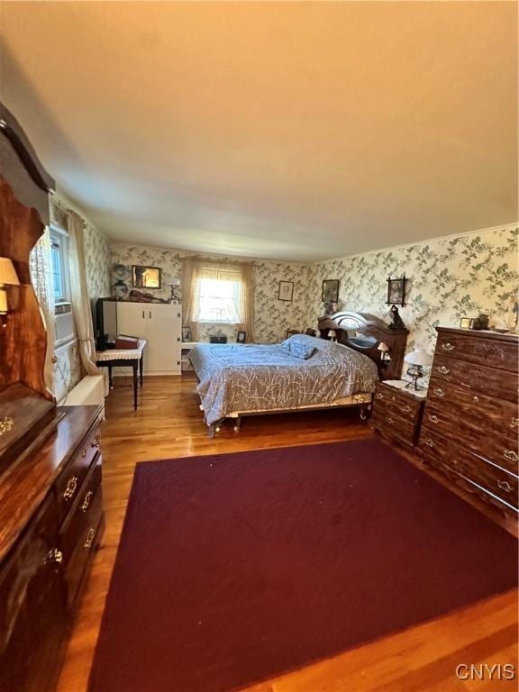 unfurnished bedroom with wood finished floors and wallpapered walls