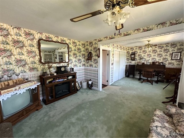 living area featuring carpet floors, wallpapered walls, ceiling fan, and wainscoting